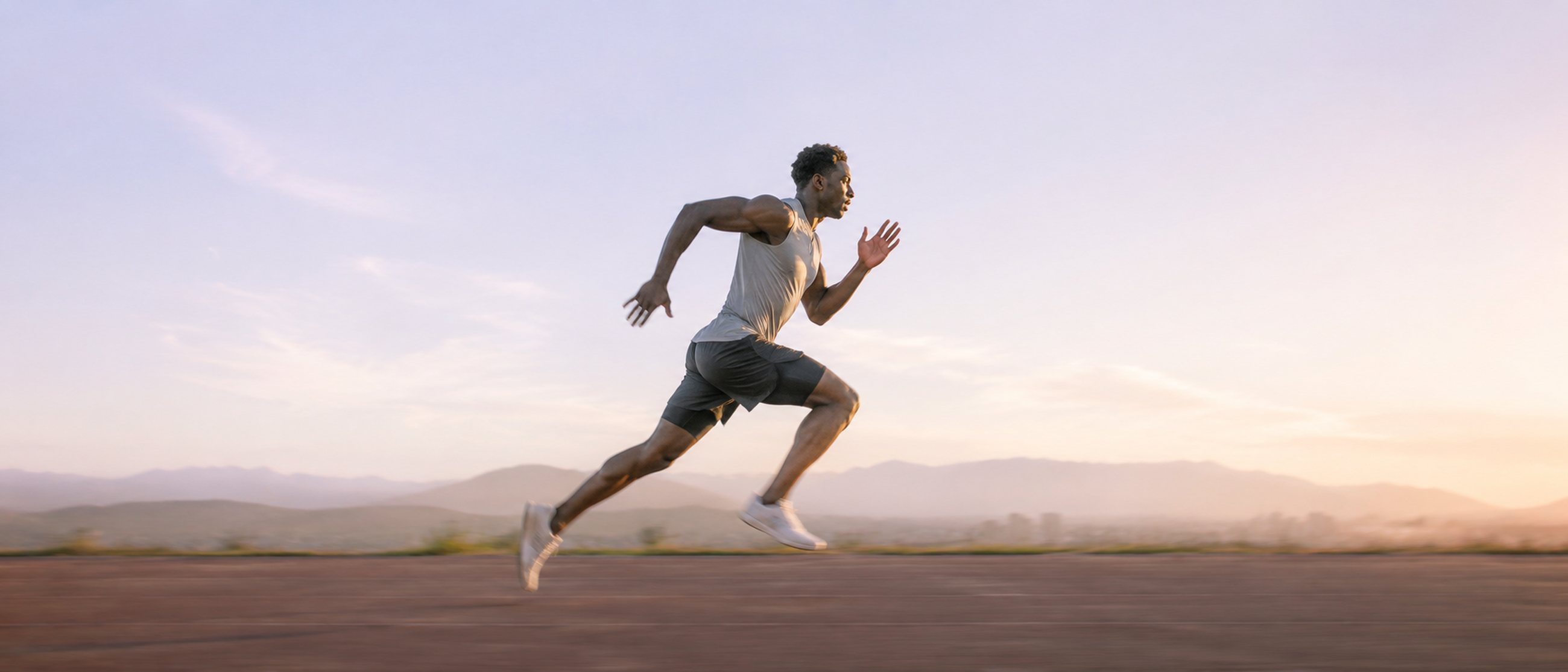 An athlete in full sprint at dawn.